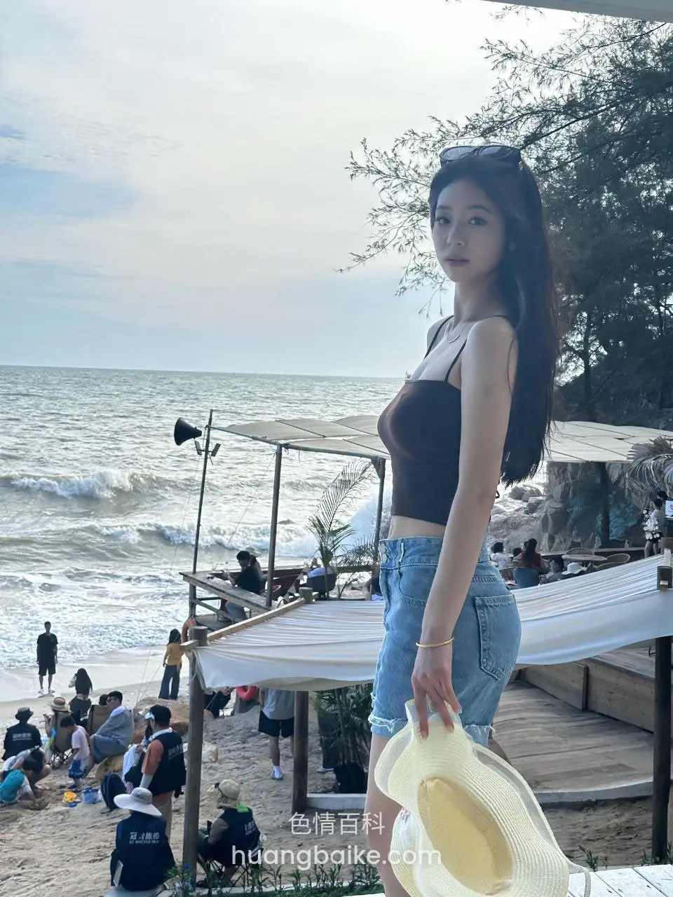 海滩边拿着帽子转身回头看镜头