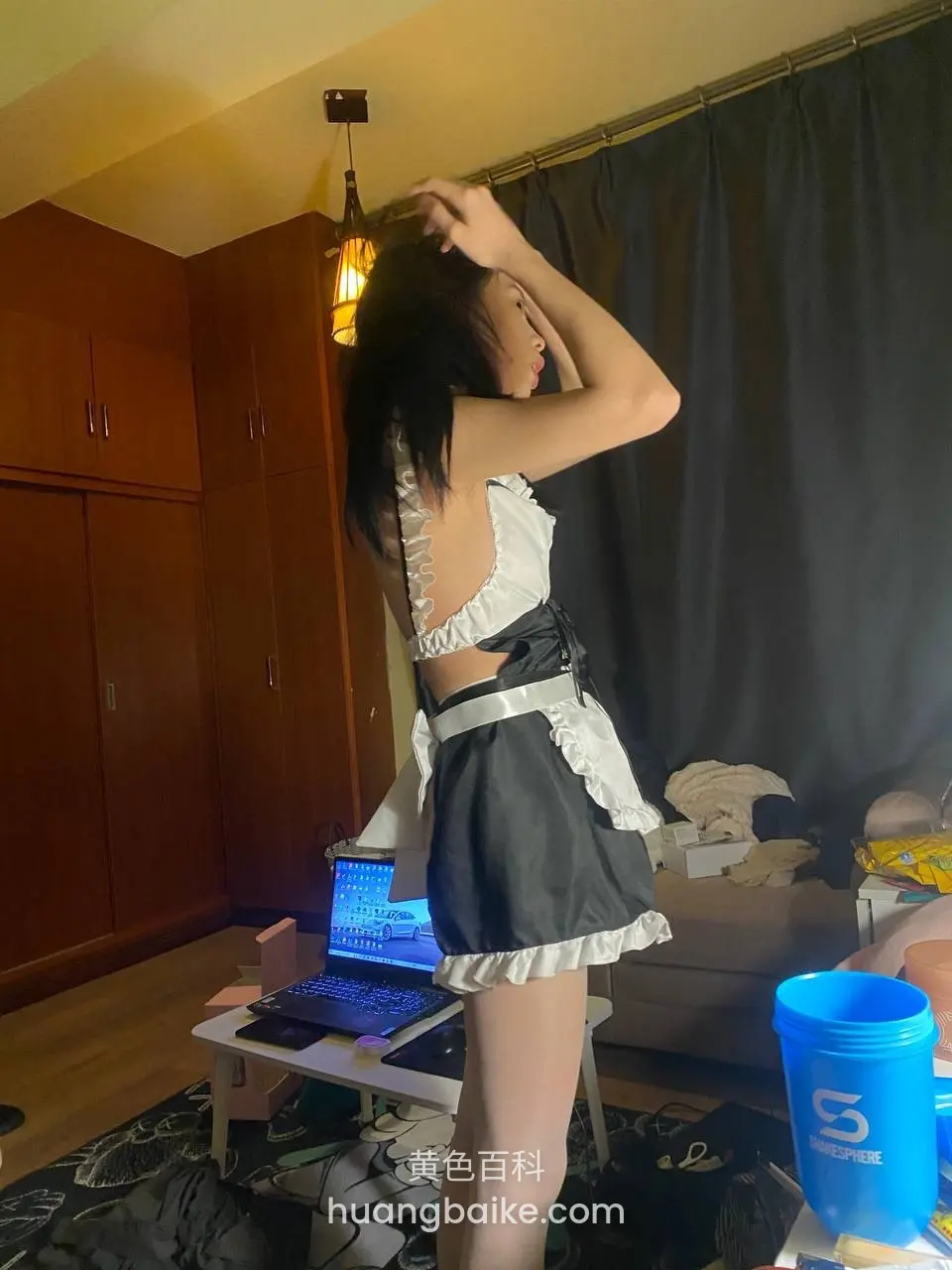 房间里站着整理头发，身后有笔记本