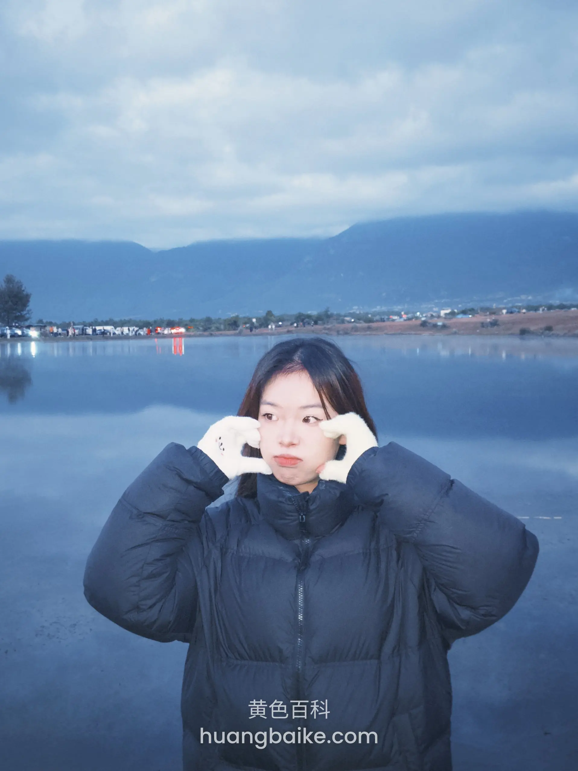 湖边山景前双手比心，穿黑色羽绒服