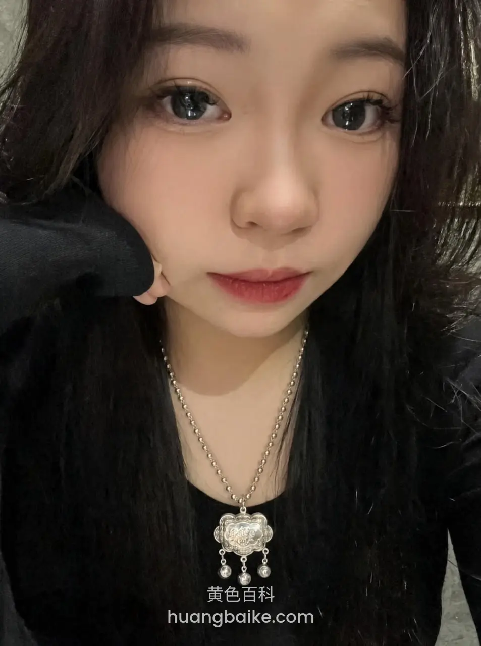 手托着脸近距离自拍，银色花朵吊坠项链显眼
