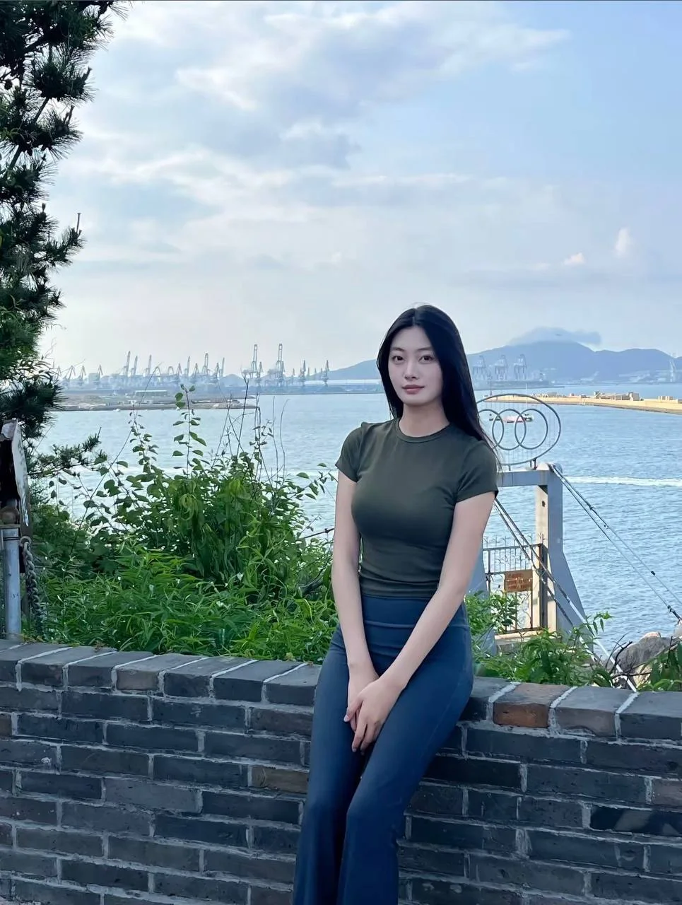 长发女生靠坐在海边砖墙上