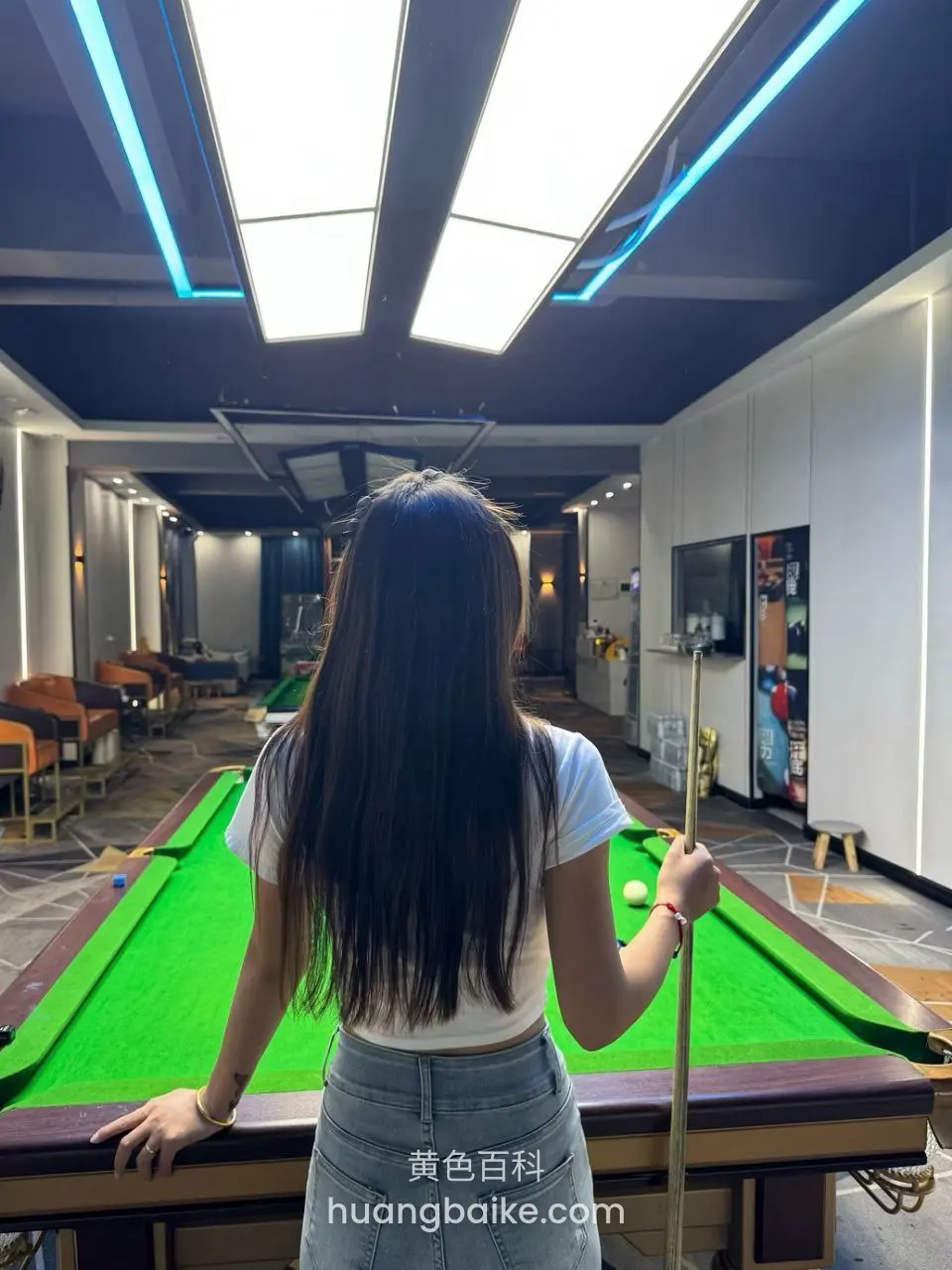 台球厅绿桌边背对镜头，手握球杆