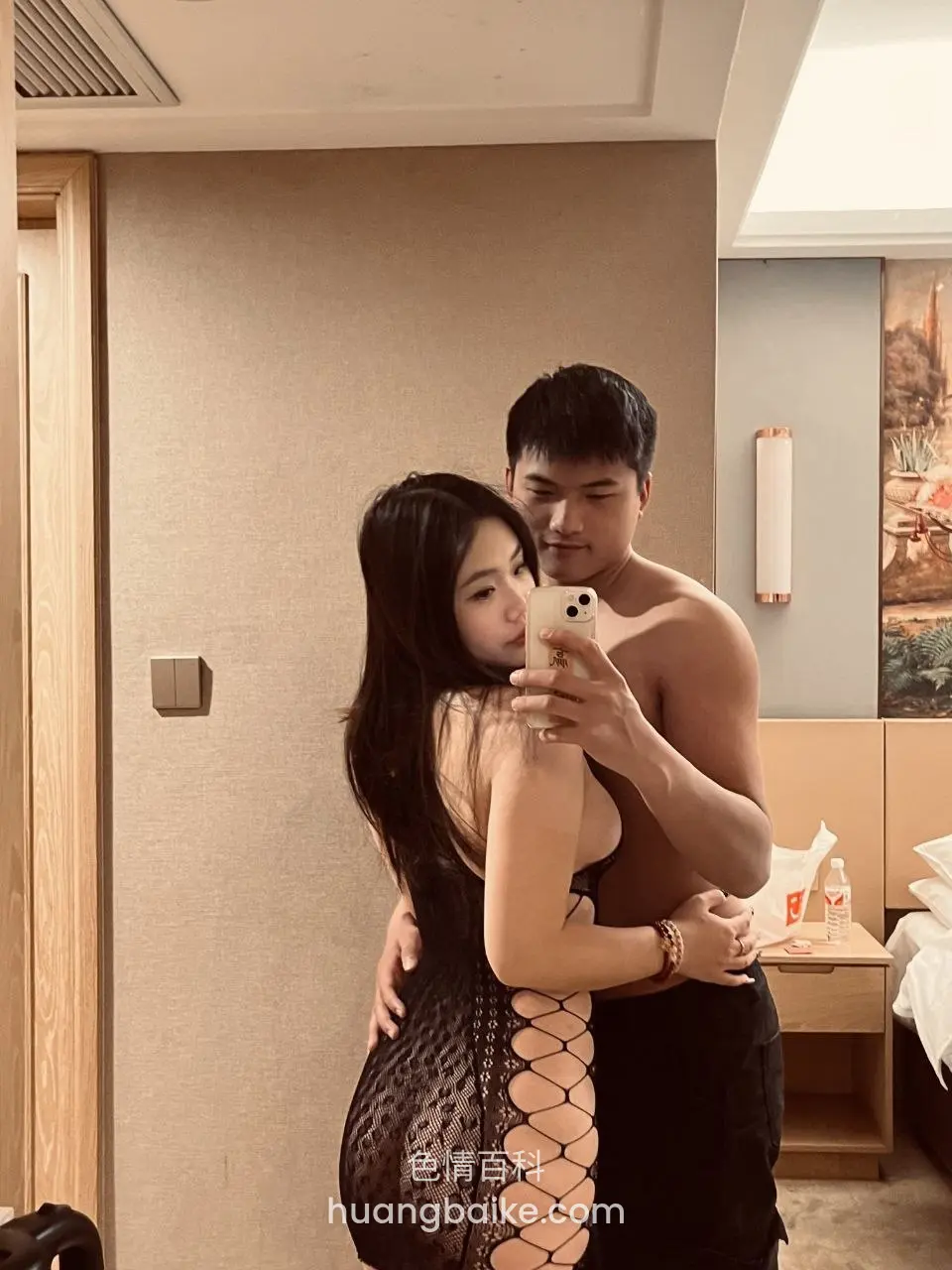 镜头对着酒店镜子，男人光着上身从后抱紧