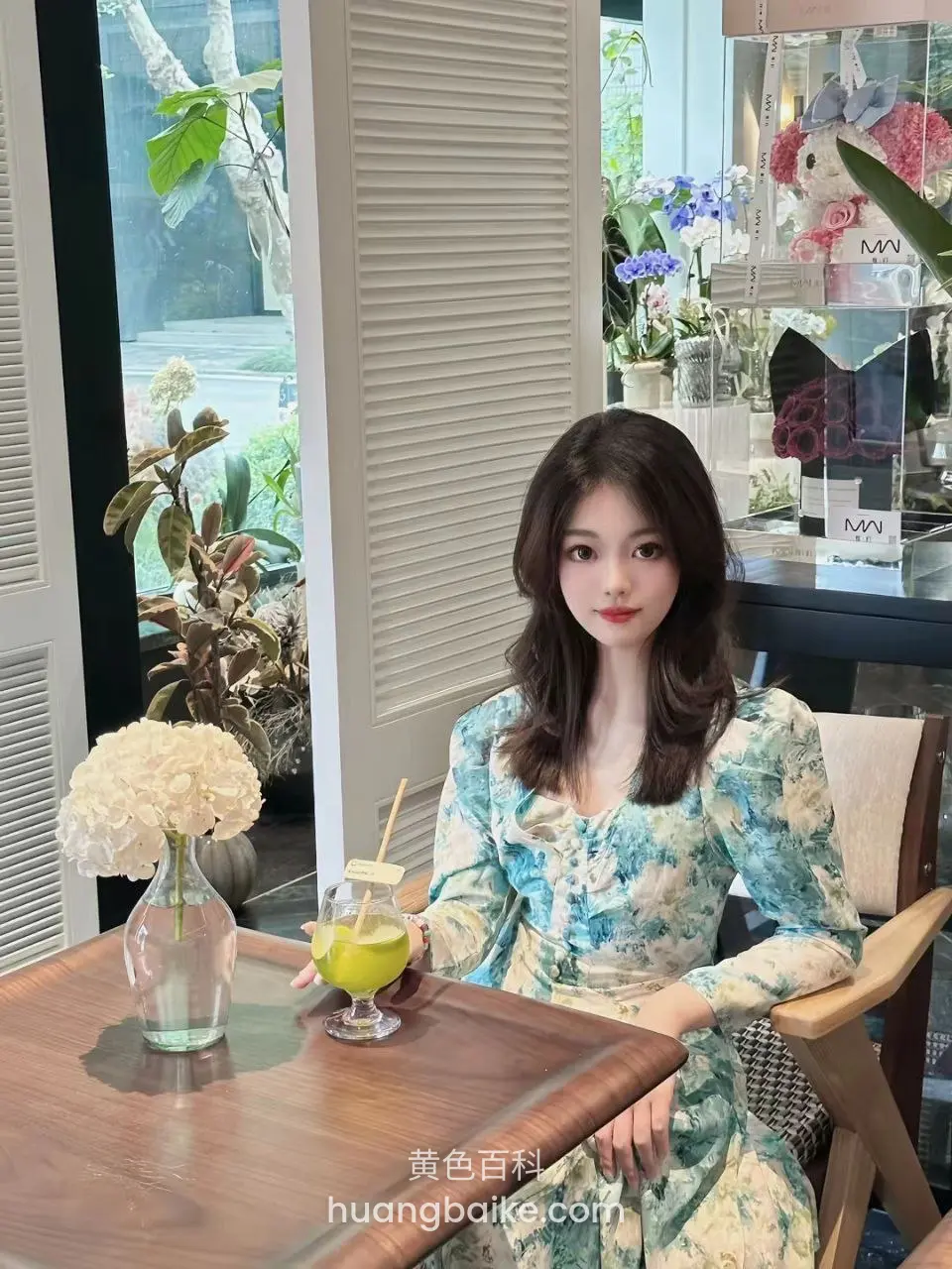 咖啡馆木桌前拿着果汁杯，桌上放着白花瓶