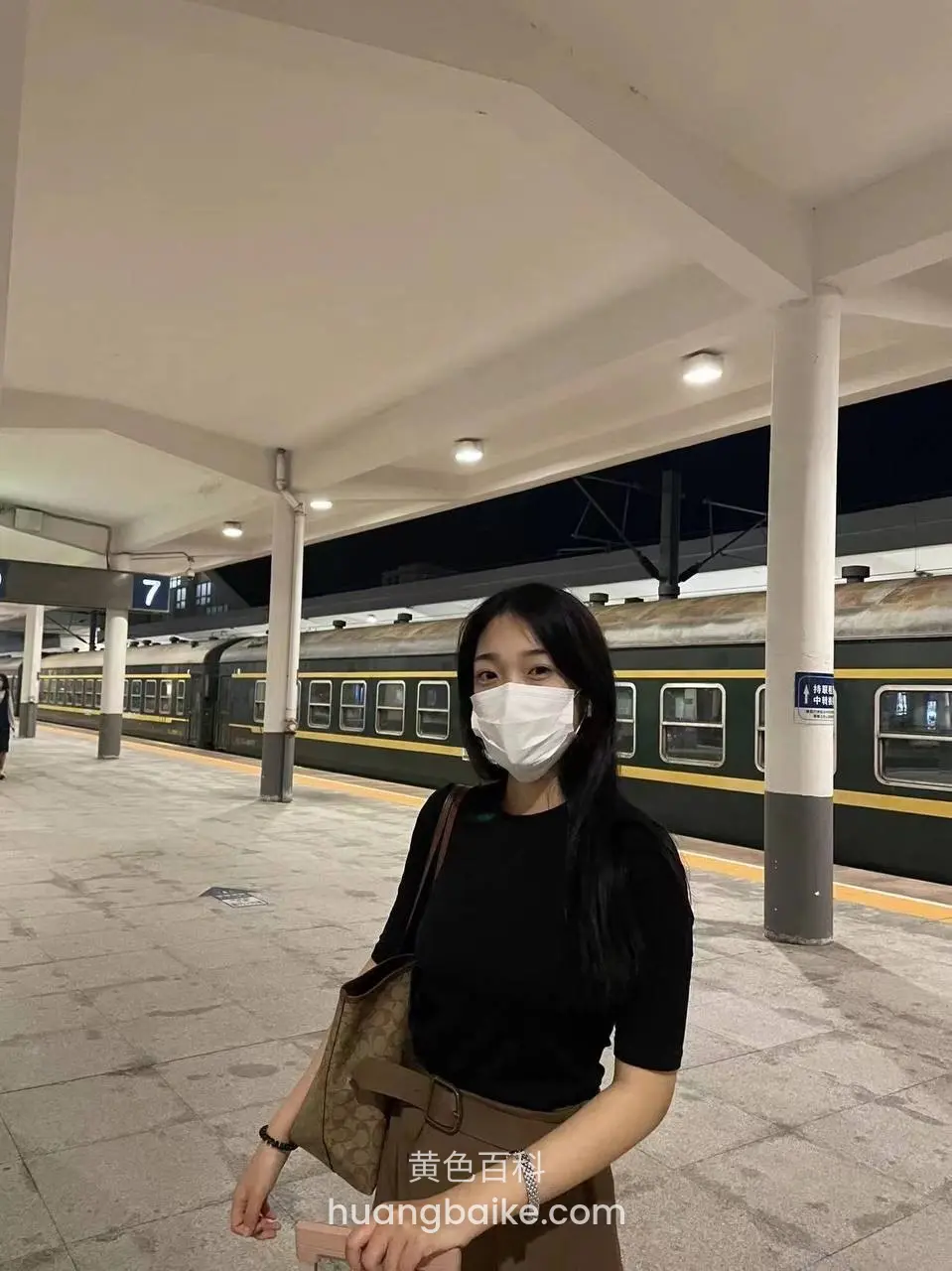 火车站台站着等车，手里拿着手机