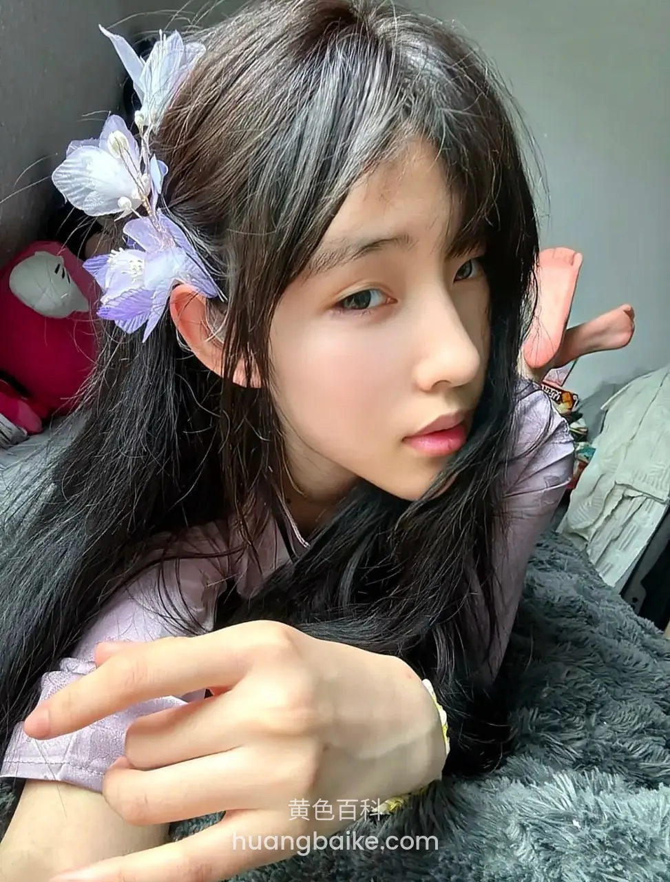 趴在灰色毯子上，手指比剪刀手
