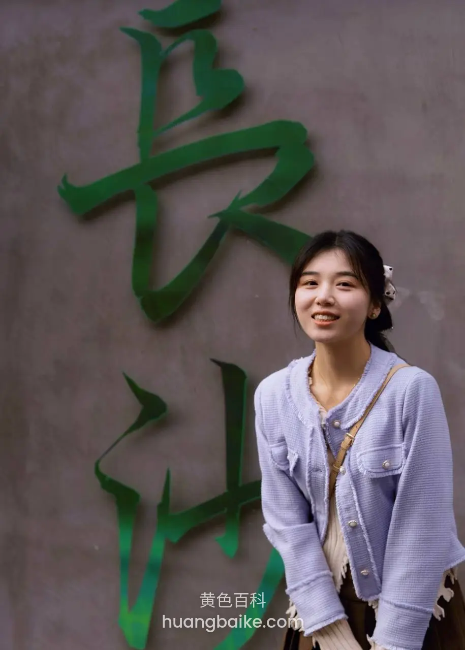 墙上巨型绿色长字前，笑着回头看镜头