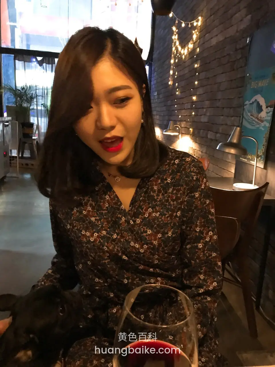 女士低头看黑狗和酒杯