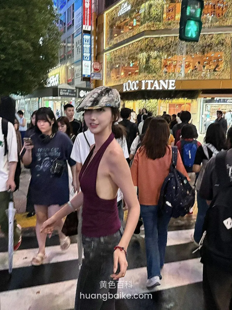 街头斑马线拿着手机，身后是DICC ITANE招牌