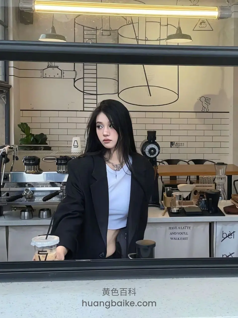 咖啡店柜台前拿咖啡杯，身后有字：HAVE A LATTE