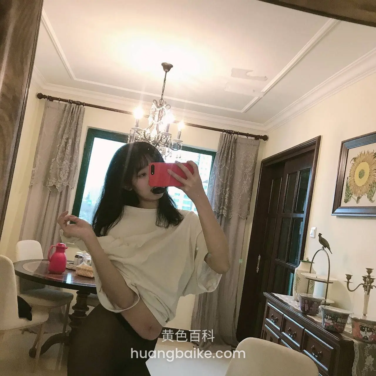 客厅吊灯下拿红手机自拍，窗帘和餐桌在后