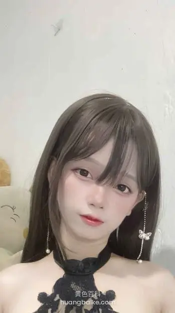 墙边近距离对着镜头看，戴着蝴蝶耳坠