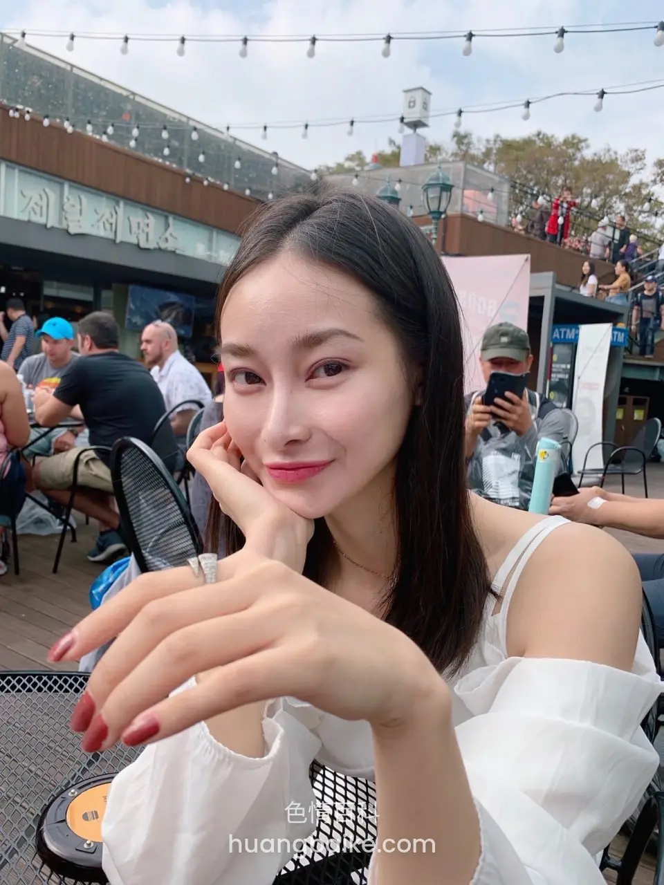 户外餐桌手托下巴，身后有韩文招牌