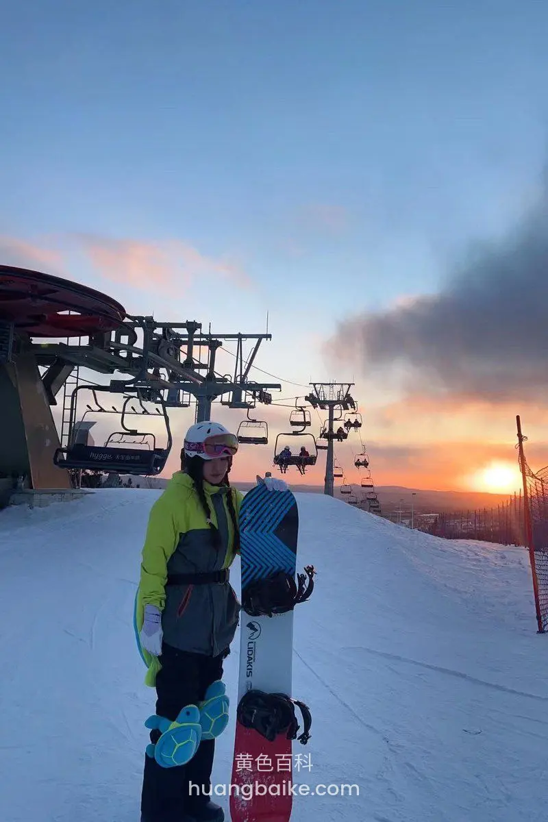 雪地缆车站旁扶着滑雪板看夕阳