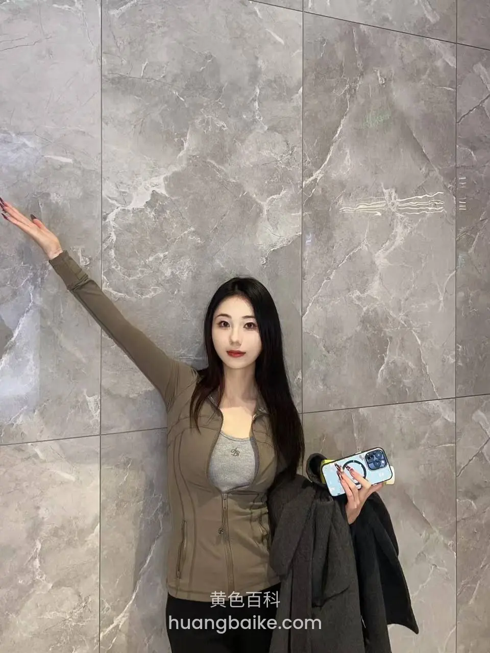 电梯间里举左手扶墙，右手拿着手机