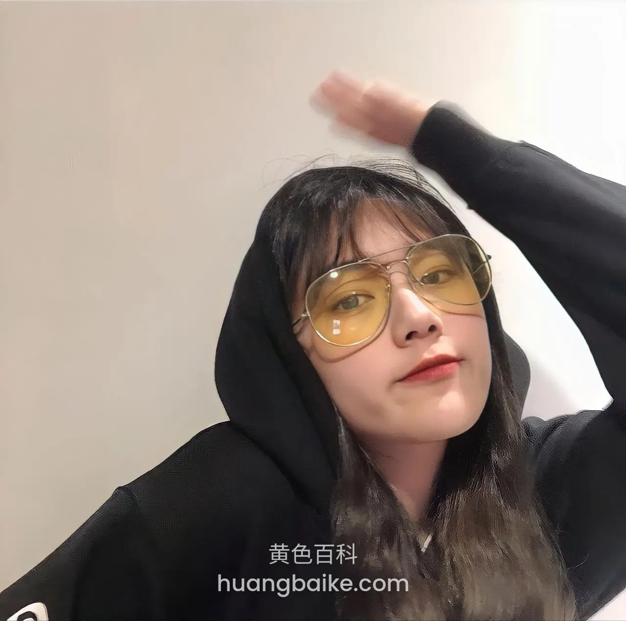 黑帽衫戴墨镜，左手举过头顶