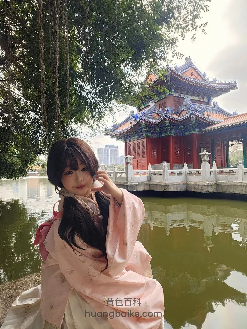 湖边古典建筑前侧身坐着，手托脸庞