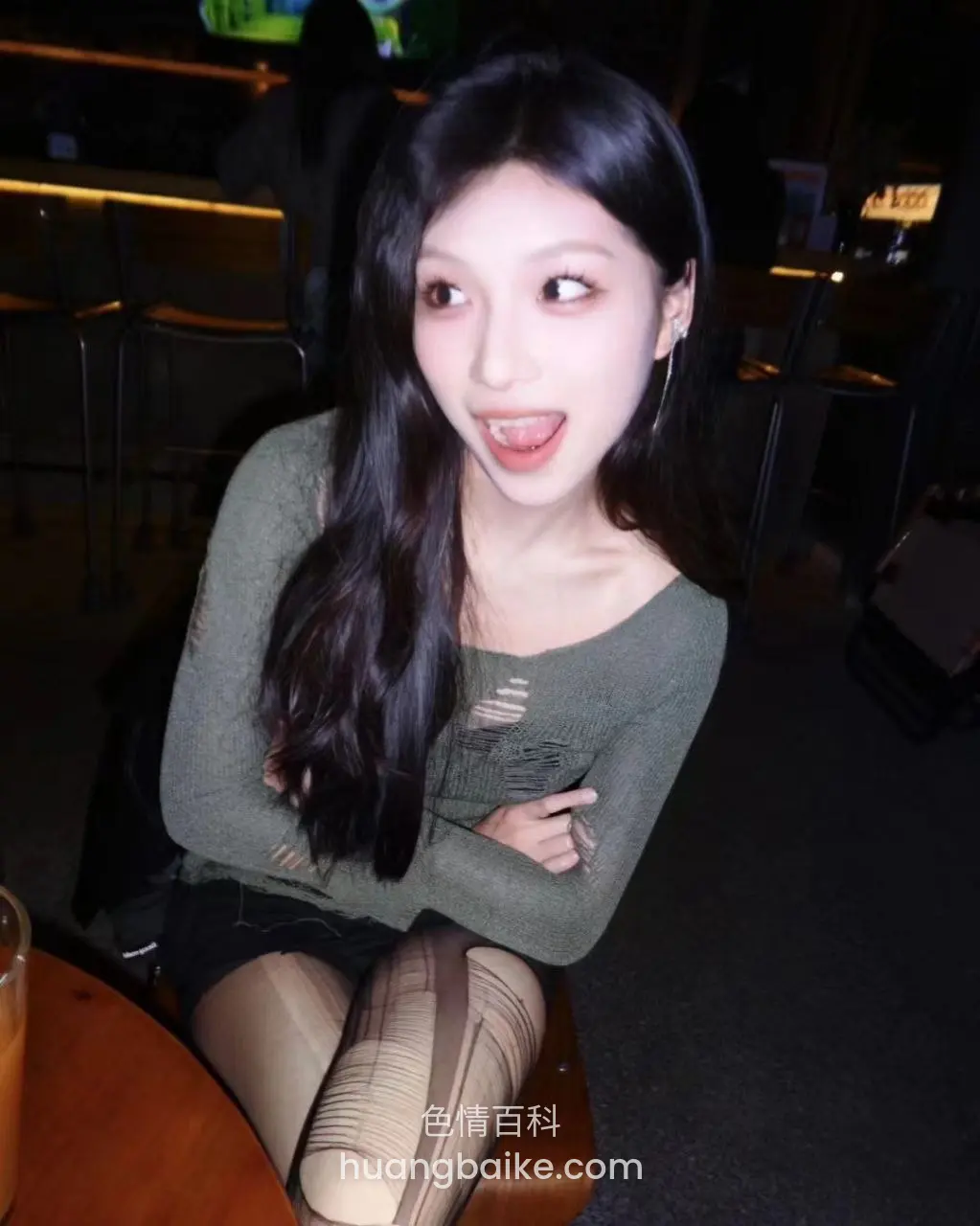 酒吧座位上抱臂伸舌头看右边