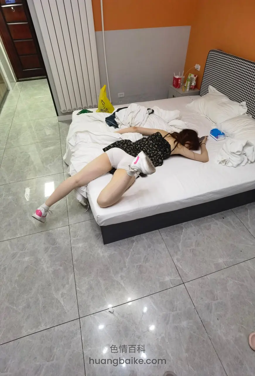 地板上远拍床铺，手里拿着手机伸懒腰