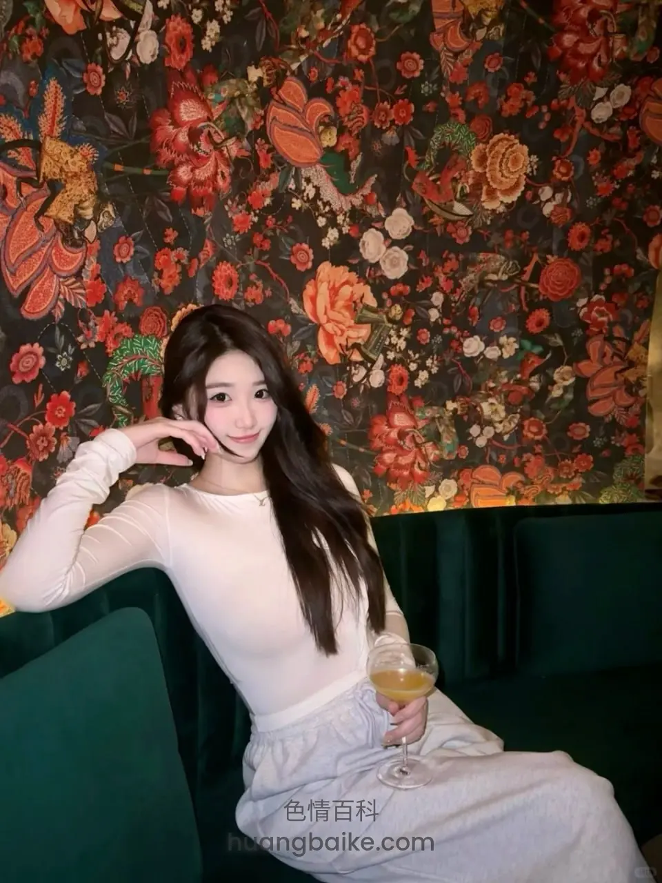 绿沙发上拿着酒杯，身后大花墙