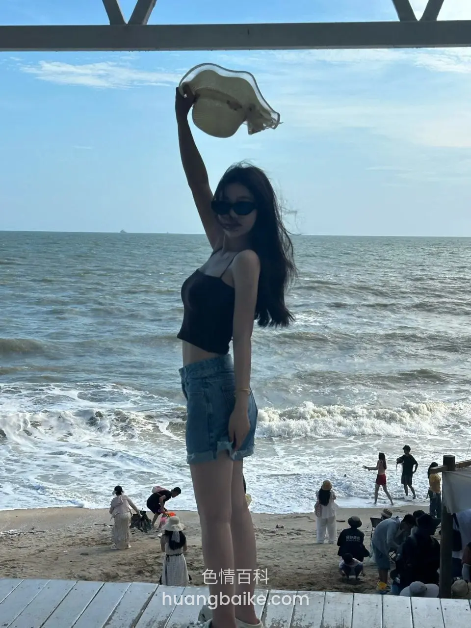 海边木板上举着帽子看海