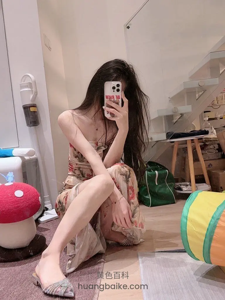 楼梯间地板坐着举手机自拍，身后有蘑菇凳和彩色玩具