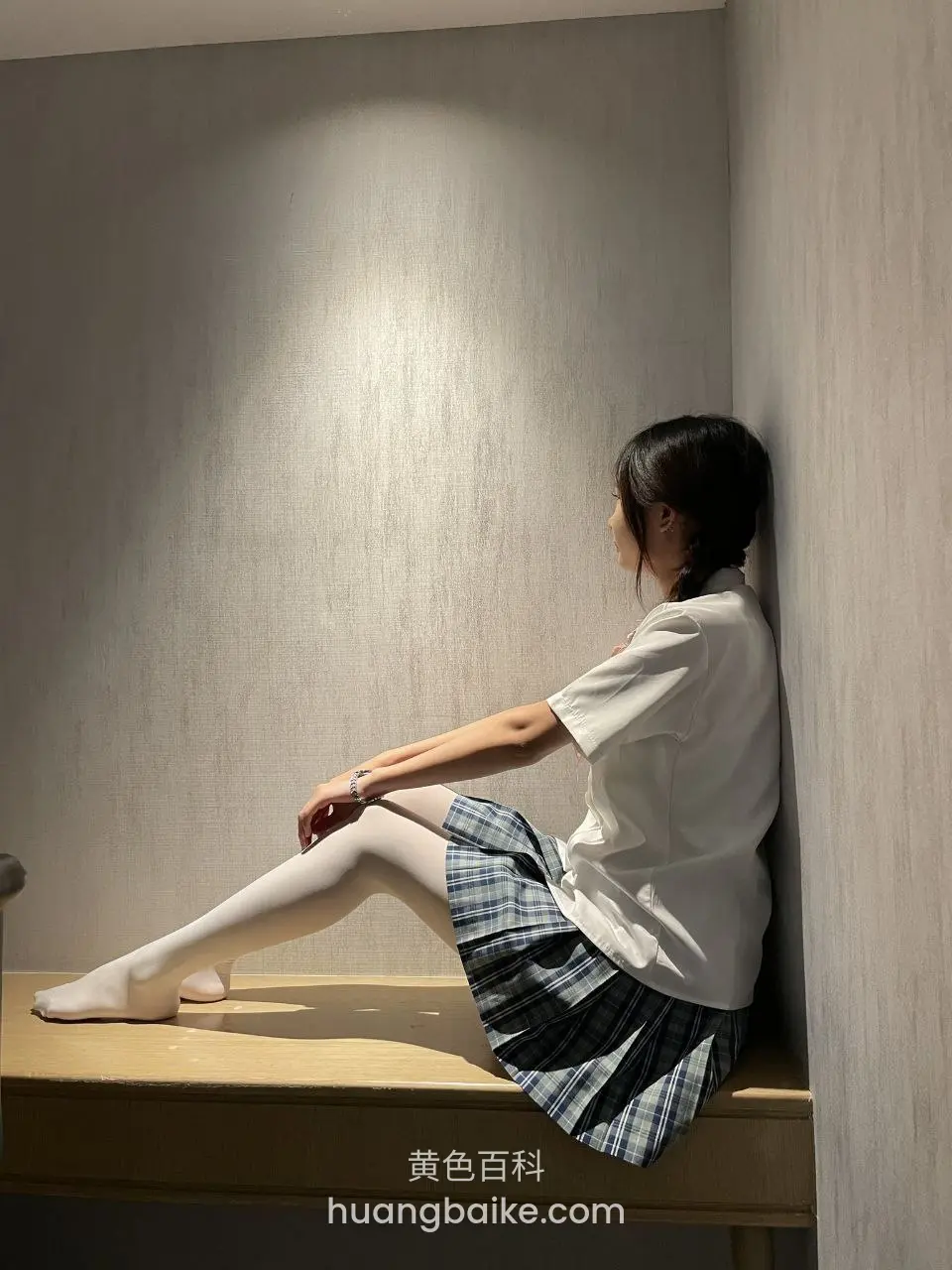 木台上侧坐靠墙，手搭在腿上