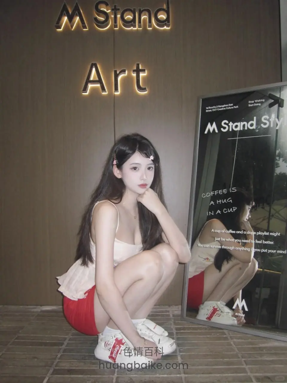 M Stand Art 墙前蹲着，手托下巴看镜头