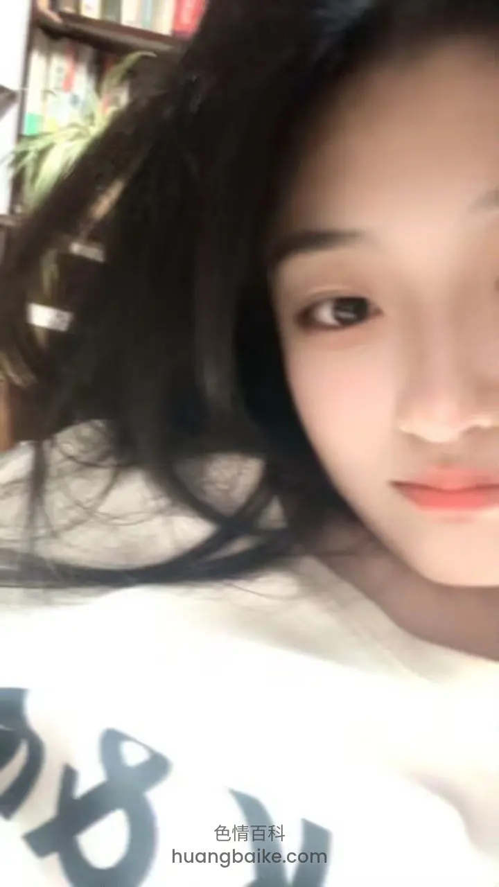 床上举着手机自拍，身后书架