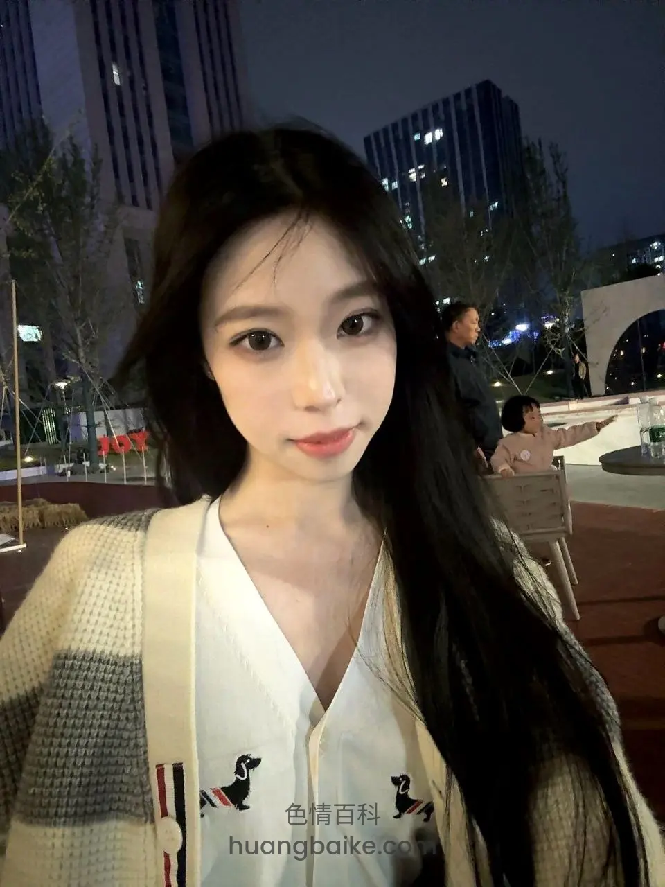 夜间城市广场，身后有行人和建筑
