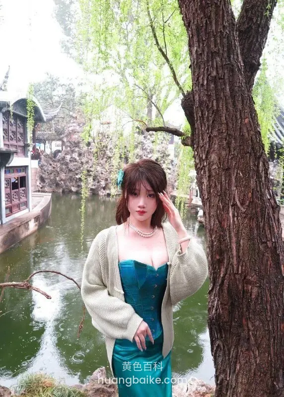 女生摸头发站在园林水边大树旁