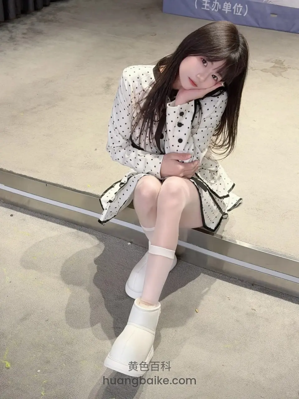 地面上坐姿手托下巴，身后蓝牌写王办单位