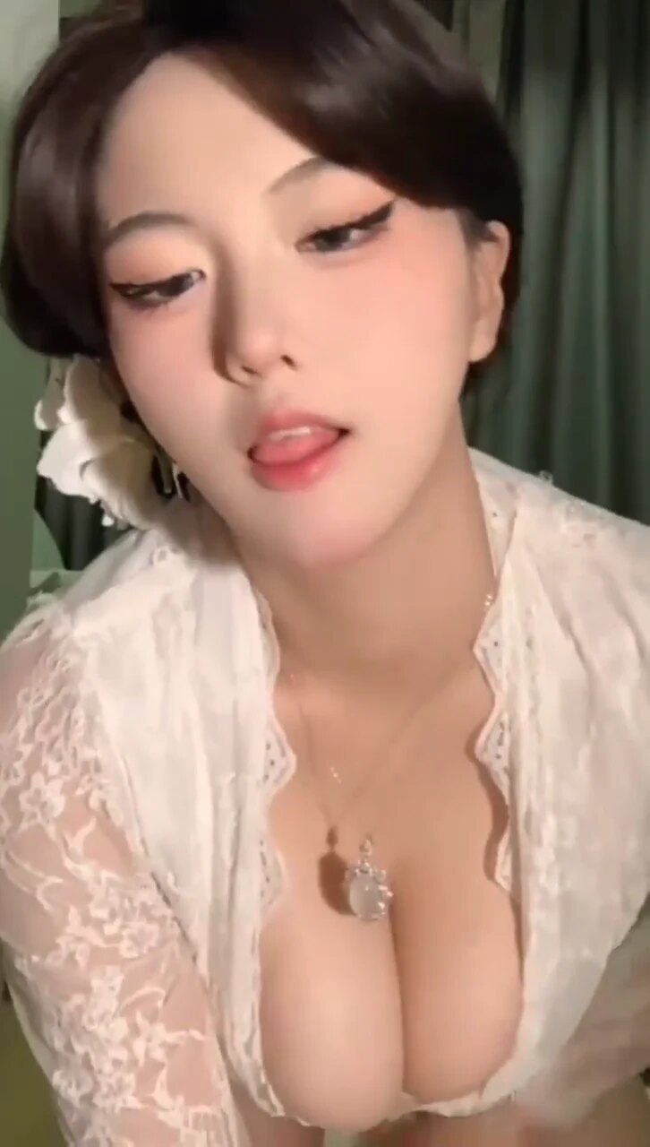 视频中主播身着性感薄纱睡裙，露出深V胸线，臀部曲线玲珑，坐在白色毛毯上挑逗镜头